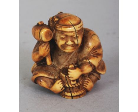 A JAPANESE MEIJI PERIOD STAINED IVORY NETSUKE OF A SEATED ARTISAN, holding aloft a mallet, 1.5in high.