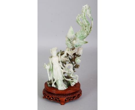 A CHINESE JADE CARVING OF GUANYIN IN THE COMPANY OF A PHOENIX, together with a fitted wood stand, the predominantly white sto