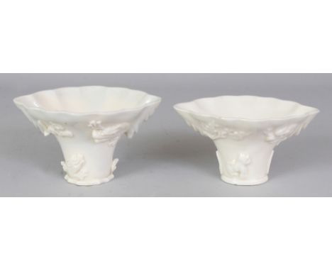 TWO SIMILAR CHINESE KANGXI PERIOD DEHUA BLANC-DE-CHINE PORCELAIN LIBATION CUPS, of rhinoceros horn form, each with underglaze