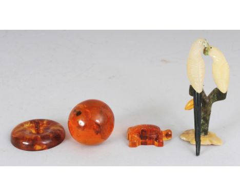 AN AMBER SPHERE, 1.5in diameter; two amber-like pieces; and a sectional model of a pair of hardstone parrots, 3.5in high. (4)