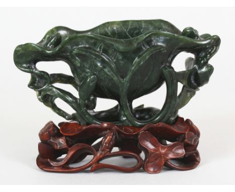 AN EARLY/MID 20TH CENTURY CHINESE SPINACH JADE MODEL OF AN OPEN LOTUS, together with a pierced and fitted hardwood stand, the