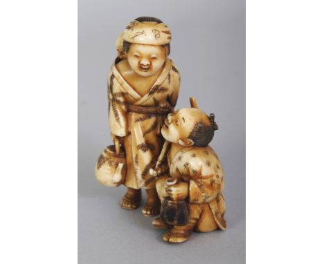 A JAPANESE MEIJI PERIOD STAINED IVORY OKIMONO OF A FAMILY GROUP, the mother and her back carried baby standing over the seate