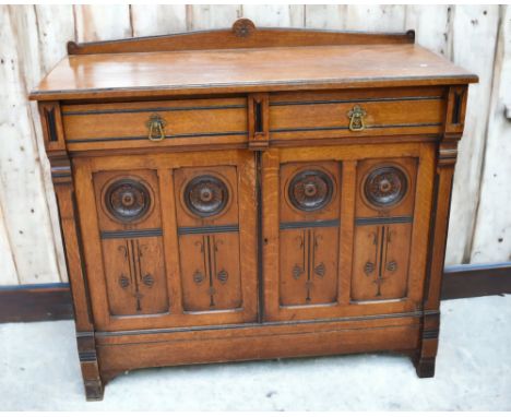 Early 20th century Oak Arts and Crafts sideboard with two drawers above two cupboard doors having ebonised and carved detail,
