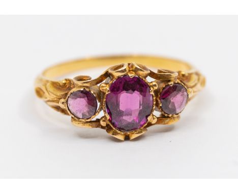 A 19th century stone set gold ring, comprising an oval mixed garnet, with small round mixed cut garnets either side, ridged b