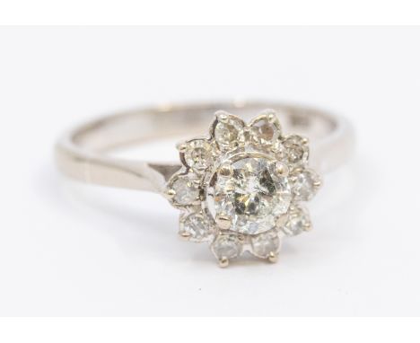 A diamond and 18ct flower head cluster ring,  comprising a central round brilliant cut diamond, approx 0.30ct, within a borde