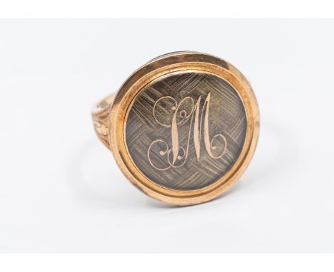 A George III rose gold mourning ring, comprising a circular mount glazed compartment set with plaited hair, with applied gold