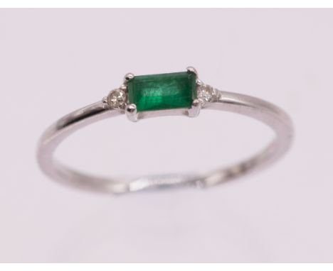 An emerald and diamond white gold ring, comprising a rectangular cut emerald, approx 5.4 x 3mm, small diamond accents set to 