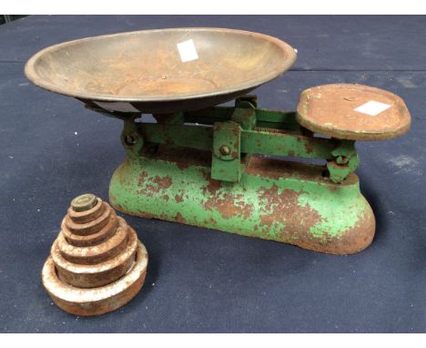 A set of green painted kitchen scales with dish and five weights (some rusting and wear)