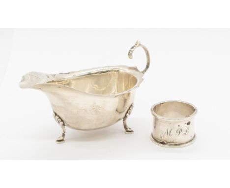 A George VI silver sauce boat, three footed, hallmarked Ernest W Haywood, Birmingham, 1940. Along with a George V silver napk