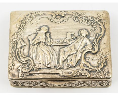 A German 800 standard silver large snuff box, the cover embossed with an 18th Century couple reclining at a table smoking and