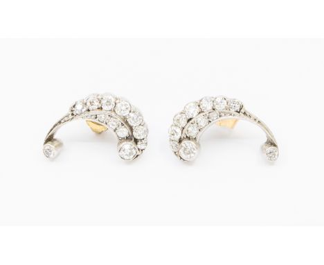 A pair of vintage platinum and diamond earrings, comprising a scroll like design, set to each terminal with an old European c