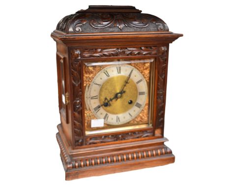 A 20th century bracket clock with presentation plaque to top, with carved detail to wooden casing.