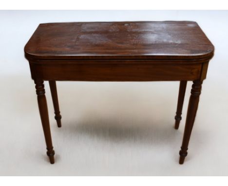 Late George III mahogany fold over card table on turned legs and green velvet playing surface.
