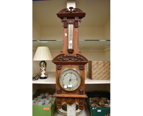 An early 20th century oak wall barometer with scrolled pediment and foliage detail
