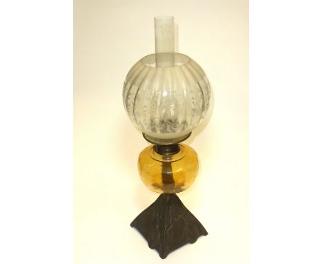 A domestic oil lamp having four-sided cast metal image of a lady cyclist, amber glass oil reservoir, decorative etched shade 