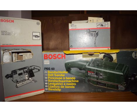 A Bosch PBS60 belt sander in original box and two attachments for a vertical and horizontal bench mounting in original boxes.