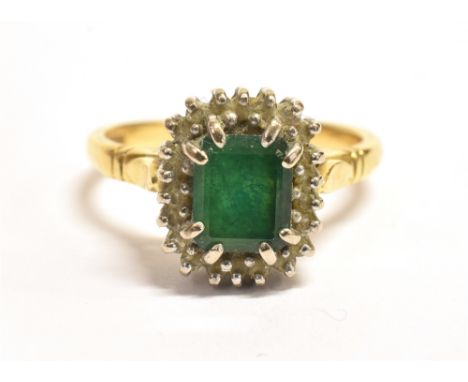 AN 18CT GOLD EMERALD CLUSTER RING The step cut Emerald measuring approx. 6 x 5mm and surrounded by numerous clear stone accen