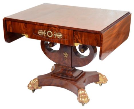 An Empire Period Mahogany Sofa Table:Mahogany with two drop leaves supported by pull out planks, a drawer set with ormolu fit