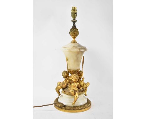 An early 20th century alabaster and gilt metal table lamp adorned with three cherubs, height to top of fitment 55cm.