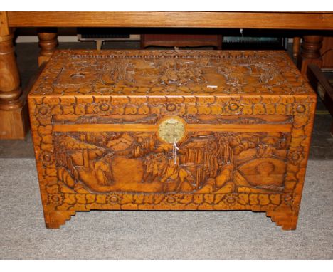 An Oriental carved camphor wood trunk, decorated figures and scenery in relief, 103cm wide x 51cm deep x 61cm high