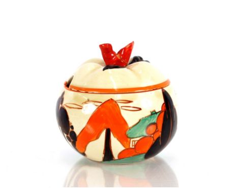 A Clarice Cliff "Bizarre" preserve pot and cover of fruit shape with bright orange, green and black cottage and tree decorati
