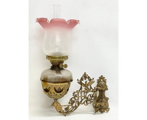 A Victorian ornate brass wall handing double burner oil lamp with later shade. 36x54cm 
