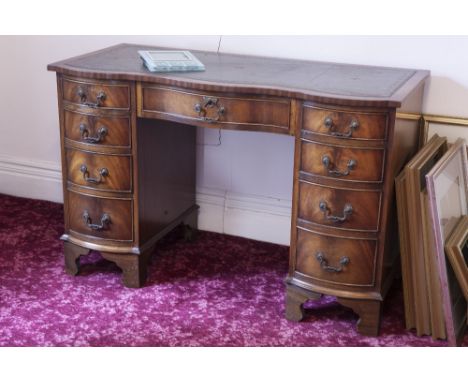 A FIGURED MAHOGANY DOUBLE PEDESTAL DESK WITH INLET LEATHER TOP, SEVEN DRAWERS TO THE SERPENTINE FRONT, ON BRACKET FEET