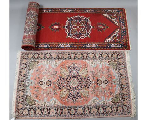 An Indian runner of crimson ground with all-over repeating multi-coloured floral design to centre within a wide border, 34.5c