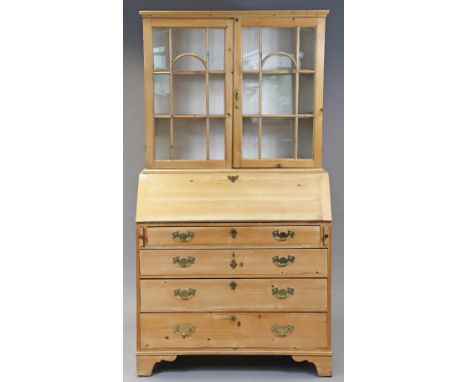 A pine tall bureau bookcase the upper part fitted two shelves enclosed by a pair of glazed doors, the base with a fitted inte