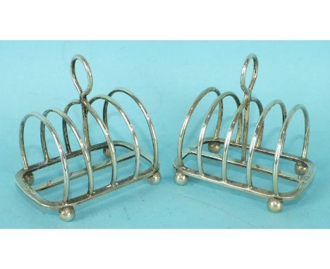 A pair of Harrods Ltd miniature silver four division toast racks on ball feet, maker R W Burbridge, London, 1933.