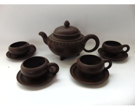 A collection of oriental dark red terracotta tea wares comprising a teapot and cover of squat form with relief border decorat