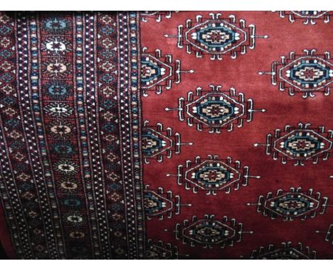 An Afghan red ground wool carpet with multi-medallion centre and set within running borders, 360 x 260 cm approx