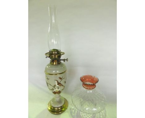 A 19th century oil burning lamp with opaque glass sectional fount with pale beige ground detailed with study of a songbird am