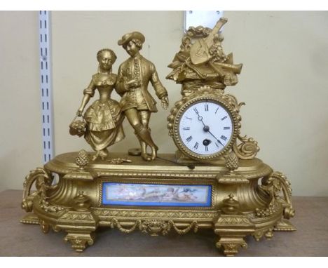 A 19th century spelter mantle clock in a romantic theme, the drum movement set within a circular case surmounted by a couple 