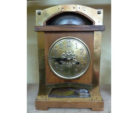 A late 19th century Arts & Crafts mantle clock in oak overlaid in brass with eight day striking movement and bell strike