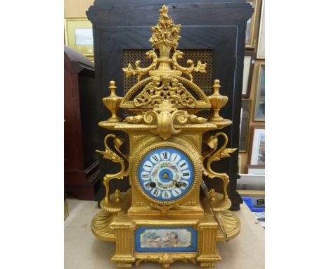 A 19th century mantle clock with gilded case, porcelain dial and panel showing a cherub enclosing an eight day striking movem
