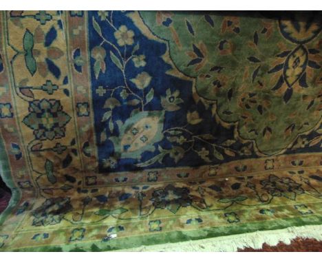 A Persian style wool carpet with geometric detail in a green, blue and beige colourway with abstract floral decoration, 350 c