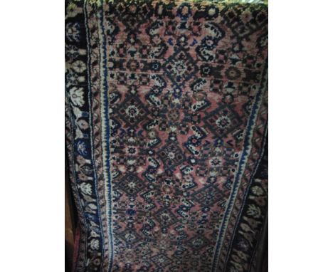 A Persian style wool runner with multi-medallion centre upon a pale pink field with alternating running border 400cm x 80cm