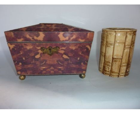 A sarcophagus shaped tea caddy constructed in faux tortoiseshell panels, raised on four brass bun supports, the hinged lid re