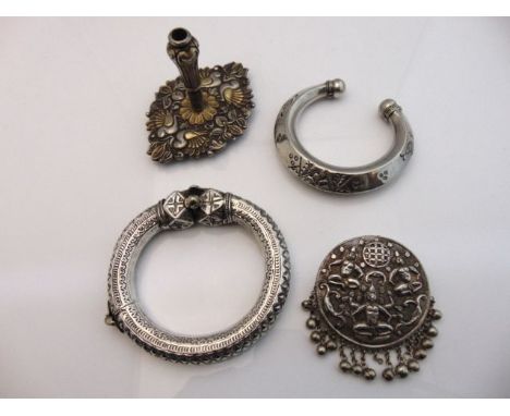 A middle Eastern silver hinged bangle, flat-chased and engraved with decorative borders; a white metal brooch, with Hindu God