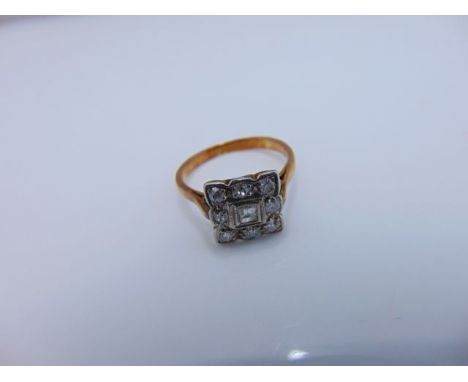 An Art Deco style diamond ring, centred with a rectangular stepped-cut diamond, within a surround of eight single- and brilli