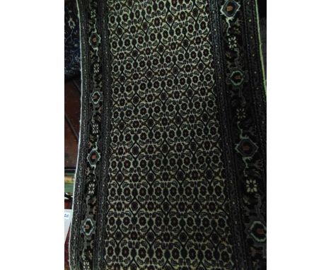 A Persian style wool runner with multi-floral panelled centre upon a white field within running borders, 305 cm x 70 cm