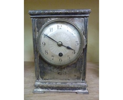 An Edwardian mantle clock in a silver plated case with engine turned dial enclosing an eight day timepiece