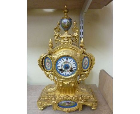 A 19th century gilded mantle clock, the shaped case with acanthus and other detail with porcelain dial, urn surmount and furt