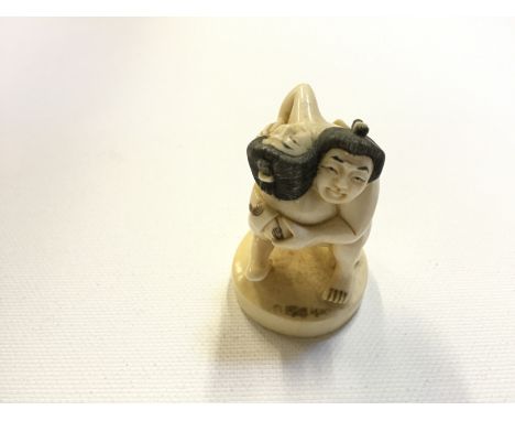 A early 19 th century ivory netsuke of two sumo wrestlers 48 mm H with mother of pearl signature insert. 