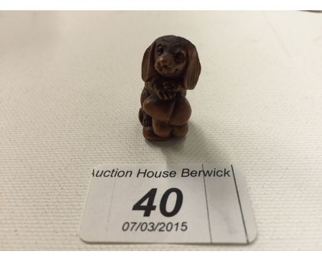 A carved wooden netsuke of a dog leaning on a toadstool 26 mm.