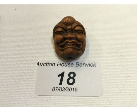 A tiny carved wooden netsuke of a face. 25 mm