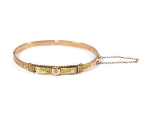 A 9 carat gold hinged bangle with diamond set heart motif and thistle decoration.  Gross weight 6.47 grams. 