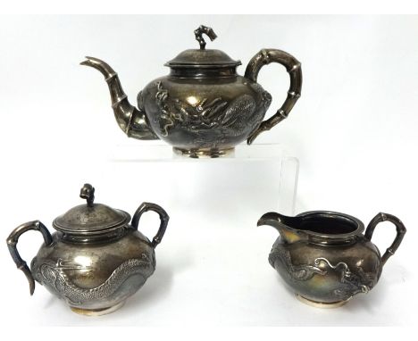 A Chinese silver tea set Hung Chong Shanghai decorated with a dragon in relief and bamboo handles inscribed 'Presented by Mem