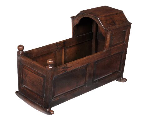 An oak rocking cradle, 18th century and later, the canopy and sleeping compartment with panel sides and on rocking rails, 79c